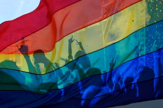 silhouette of a parade of gays and lesbians with a rainbow flag - symbol of love and tolerance