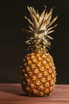 Pineapple is on the table on a dark background.