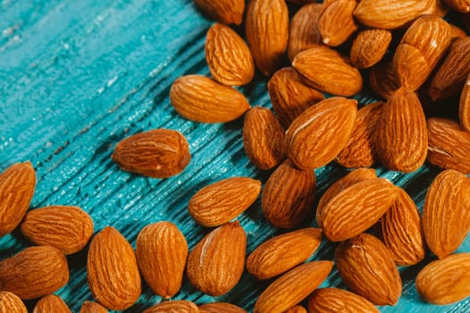 handful of almonds on a blue wooden background.