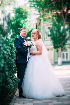 bride and groom on the background of the garden fence.