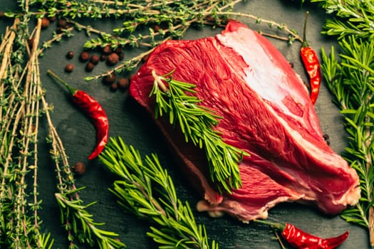 raw beef meat with spices on slate stone kitchen board.