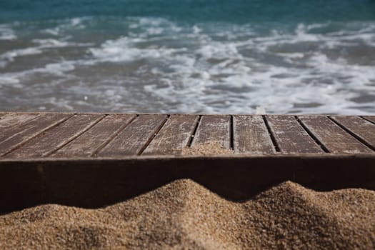 wooden plank in sand and blue sea in the background