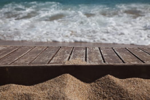 wooden plank in sand and blue sea in the background