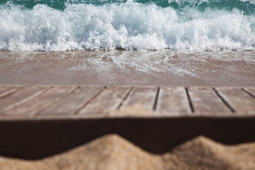 wooden plank in sand and blue sea in the background