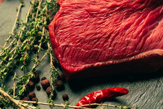 raw beef meat with spices on slate stone kitchen board.