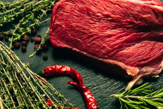 raw beef meat with spices on slate stone kitchen board.