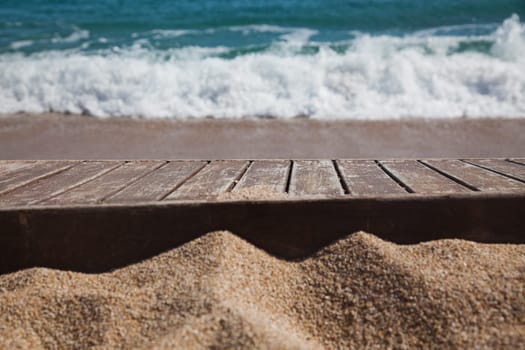 wooden plank in sand and blue sea in the background