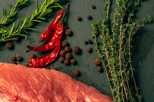 raw pork meat with spices on slate stone kitchen board.