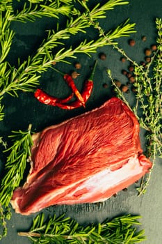 raw beef meat with spices on slate stone kitchen board.