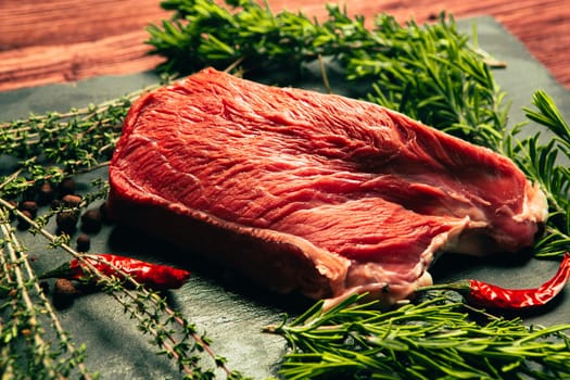 raw beef meat with spices on slate stone kitchen board.