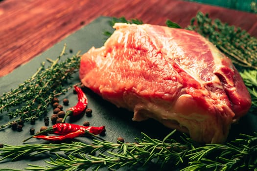 raw pork meat with spices on slate stone kitchen board.
