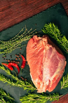 raw pork meat with spices on slate stone kitchen board.