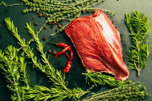 raw beef meat with spices on slate stone kitchen board.