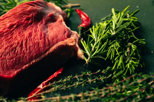 raw beef meat with spices on slate stone kitchen board.