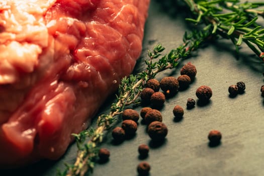 raw pork meat with spices on slate stone kitchen board.
