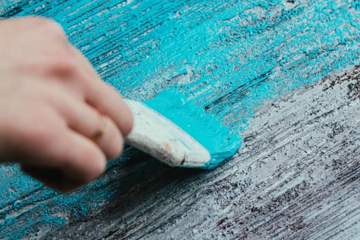 closeup hand use brush paint white blue on wood surface.
