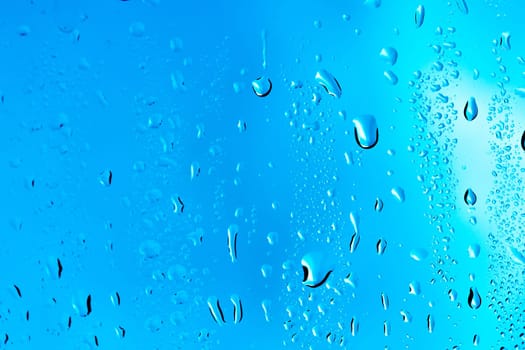 Drops on the glass rain blue background.