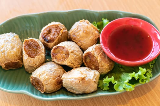 Hoi Jo, Deep Fried Crab Meat Rolls with sweet plum sauce. Thai street food and restaurant cuisine on wooden table.