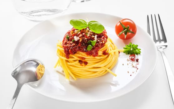 Spaghetti Bolognaise with coiled pasta topped with basil, tomato and grated parmesan cheese