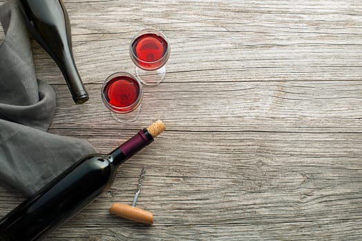 Bottle of red wine with label on old board. Glass of wine and cork. Wine bottle mockup. Top view