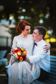 groom and the bride against the trees of the park.