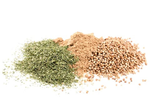 Pile of dried cilantro leaves, whole coriander seeds and coriander powder.  Isolated on a white background.