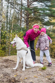 Granny with her granddaughter and a dog walk in autumn Park