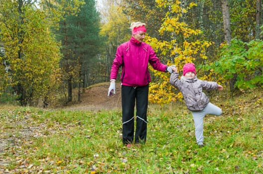 Woman with girl doing aerobics in the autumn park