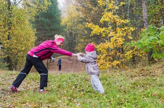 Woman with girl doing aerobics in the autumn park