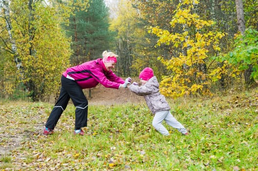 Woman with girl doing aerobics in the autumn park