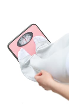 Young woman stands on scales and measures weight on a white background. Concept of healthy lifestyle.