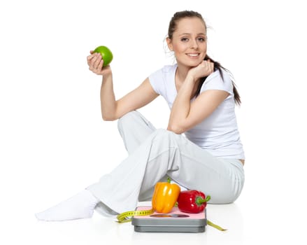 Sporty young woman with scales, fresh peppers and apple on a white background. Concept of healthy lifestyle.