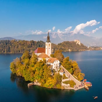 Bled island on lake Bled, and Bled castle and mountains in background, Slovenia, Europe.