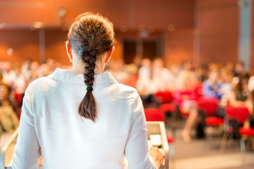 Female academic professor lecturing at Conference. Audience at the lecture hall.