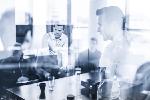 Business team brainstorming on meeting in modern corporate office. Business executive delivering presentation to colleagues during in-house training. Business and entrepreneurship. Blue toned.