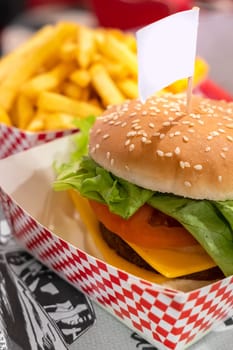 Vegetarian burger, with space for text in empty label (flag) . Vegan meat. On defocused blurry background the fries.