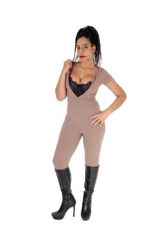 A beautiful young woman standing in a beige color jumpsuit and big.boobs and high heels, isolated for white background.