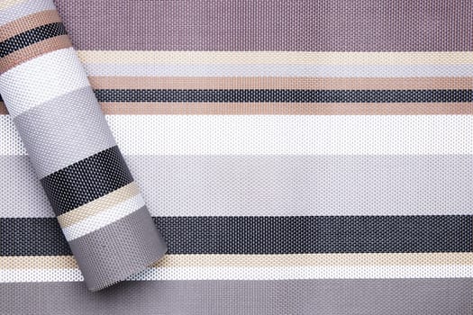 Striped background. Top view of details of colorful horizontal striped and a role of same pattern on left background texture with seamless pattern on plastic tissue. Macro.