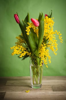 Spring bouquet with mimosa and tulips in a vase