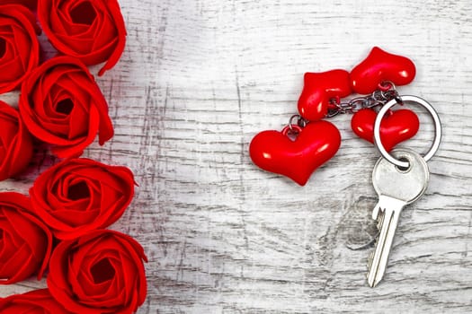 Lovely red roses and a key on the wooden background