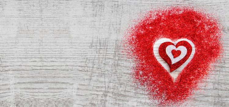 Heart shaped red sparkles on wooden background