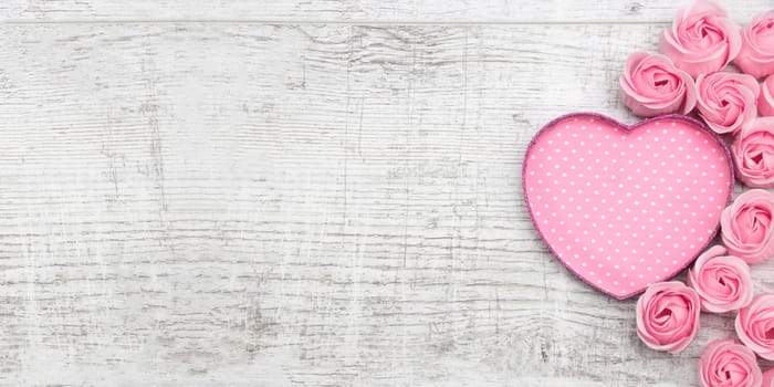 Pink roses and note paper on the wooden background