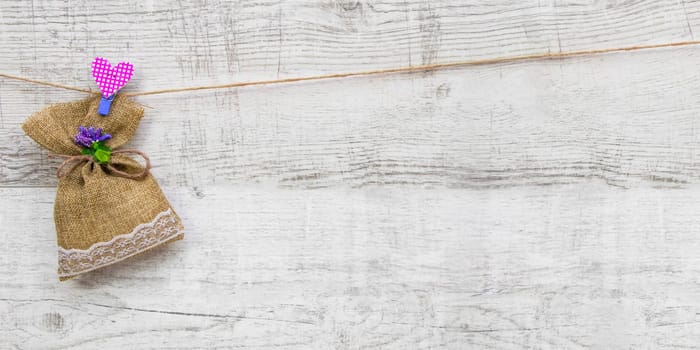 Small gift sack with heart note in wooden background