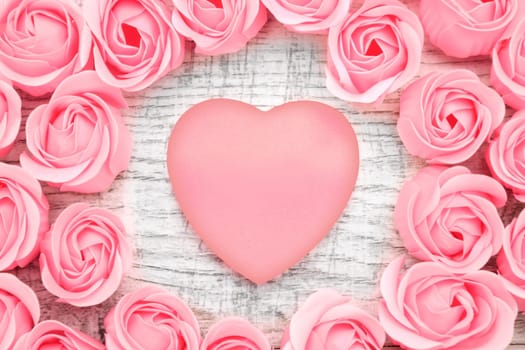 Pink roses and note paper on the wooden background