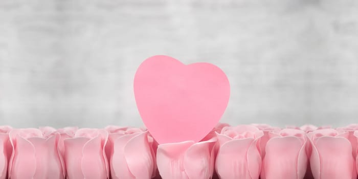 Pink roses and note paper on the wooden background