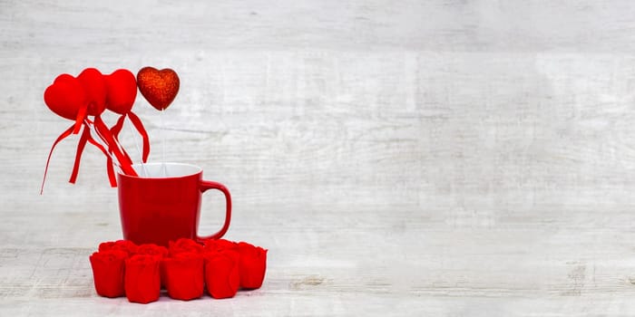 Shiny red coffee cup and red roses on wooden background