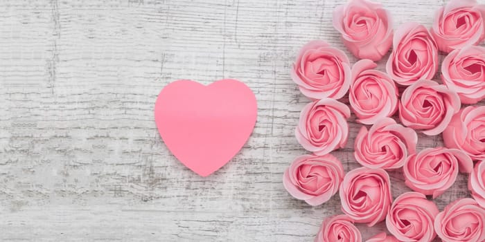 Pink roses and note paper on the wooden background
