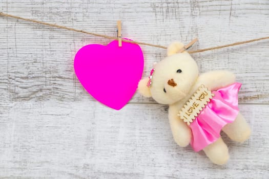 Little pink heart and teddy bear hanging on rope