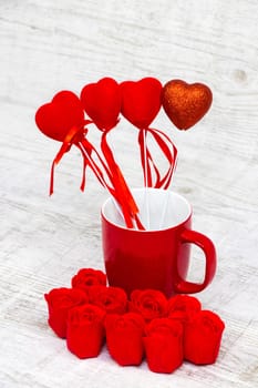 Shiny red coffee cup and red roses on wooden background