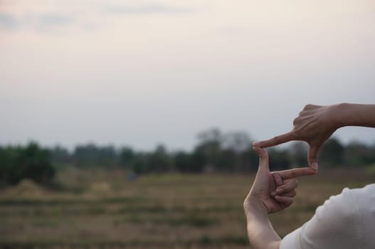 Hands making frame with sunset. Close up of woman hands making frame gesture.